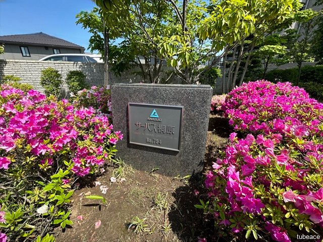 四季の花々に囲まれたマンションサイン。植栽の手入れが行き届いており、管理の良さがうかがえます。